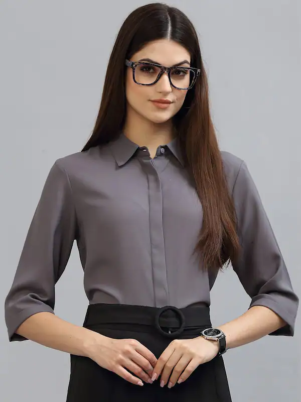 A woman wearing a dark color pent, collared shirt, watch, and black glass